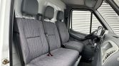 Three-gray fabric seats in the front of a white van, with seat belts and a right-hand driver area visible on the right.
