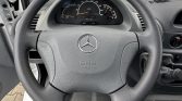 Close-up of a gray Mercedes steering wheel with SRS Airbag emblem; speedometer and dashboard visible behind.