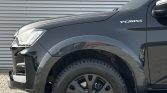 Front-left quarter of a dark gray Y-CROSS pickup, showing headlight, fender with 'Y-CROSS' badge, and a rugged alloy wheel.