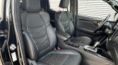 Black leather front seats and center console inside a car, with steering wheel and gear shifter visible.