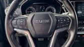 Isuzu steering wheel with built-in control buttons and stitched leather, dashboard display visible behind it.