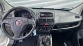 Interior of a Fiat car showing the steering wheel, center console with radio, climate controls, and a manual gear stick in the foreground