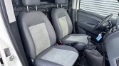 Interior of a white van showing driver and front passenger seats, gear shift, and steering wheel.