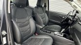 Front interior of a car showing black leather driver and passenger seats, center console, and steering wheel.