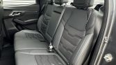 Rear row of a car with black leather seats, three seating positions, and headrests; visible seat belts ready for passengers.