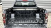 Rear view of a black pickup with the tailgate down, showing an empty truck bed with a loose strap across the floor.