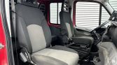 Interior of a red truck cab with two gray fabric seats; steering wheel on the right and dashboard in view.