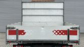Rear view of a metal cargo trailer with diamond-plate sides and a red reflective stripe on white panels