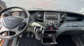 Driver's cockpit of an orange Iveco Daily van with steering wheel, dashboard controls, and manual gear lever.