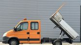 Orange dump truck with its bed raised, ready to unload on a paved surface.