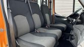 Interior of an orange van with three front seats, each with a seat belt, and the driver’s area visible to the right