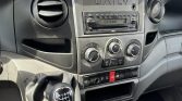 Interior of a vehicle dashboard with a manual gear stick and central control panel including radio and climate controls labeled DAILY on the radio unit
