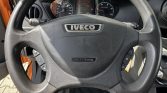 Steering wheel with Iveco logo and airbag cover, dashboard gauges behind.