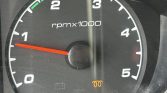 Car tachometer: needle around 1 on the rpm x1000 scale, with green zone above, orange warning light symbols faint below.