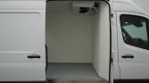Open cargo van with empty white interior and speckled floor, right-side sliding door aligned with driver cab partial view.