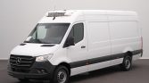 Front three-quarter view of a white Mercedes-Benz cargo van with a rooftop refrigeration unit, parked indoors into a gray background.