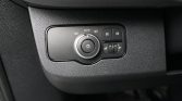 Car headlight control panel on a textured dashboard, featuring an adjustable dial set to auto with fog-light buttons nearby