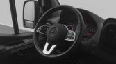 Close-up of a Mercedes steering wheel in a van, with instrument cluster and side mirror visible in the background.