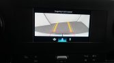 Car rearview camera screen showing parking guide lines (yellow) and danger zone (red) as you back up; dashboard icons below.
