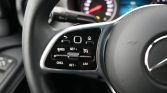 Close-up of steering wheel control panel with cruise control buttons in a car.