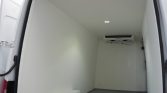 Interior of a white refrigerated cargo van with insulated walls and a ceiling light at the center.