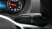 Close-up of a car's automatic transmission shift lever showing R N D P on the knob, with a blurred dashboard in the background.