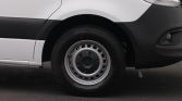 Side view of a white van showing the front left wheel and wheel well.