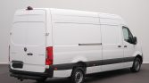 White Mercedes-Benz Sprinter cargo van shown from rear-right, parked on dark pavement with closed rear doors and side panel visible the length of the van, in a studio setting.