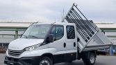 White Iveco dump truck with a raised, tilting metal bed in an industrial yard
