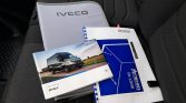 Iveco vehicle manuals and a blue spiral-bound folder on a dark car seat surface организ?
