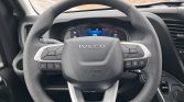 Steering wheel with perforated black grip and silver spokes, center logo says IVECO, inside dashboard visible behind.