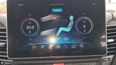 Car climate control touchscreen showing dual-zone settings: left dial at 20.5°C, right dial with fan speed set to 5, blue seat icon in the center indicating heated/seated climate control, and a.CLIMATE label above.