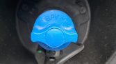 Blue unleaded fuel cap inside the car's fuel filler area, with 'unleaded' embossed on it (close-up).