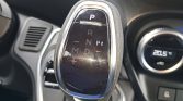 Automatic gear selector in a car interior showing P R N D with +/- for manual mode and a glossy black surface with chrome edges