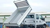 Dump truck with its raised bed ready to unload, in an industrial yard.