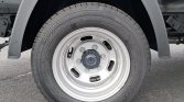 Close-up of a vehicle wheel: steel rim with six lug nuts and a Continental tire mounted on a truck/military-style wheel well area with fender above.
