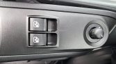 Close-up of a car's driver-side door panel with two power window switches and a circular side-mirror adjustment knob