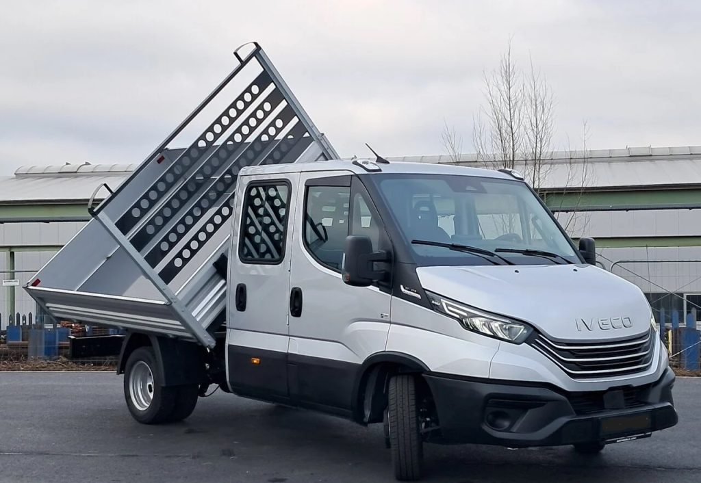 Iveco tipper truck with a raised metal dumping bed, parked in an outdoor lot.