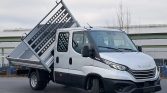 Iveco tipper truck with a raised metal dumping bed, parked in an outdoor lot.