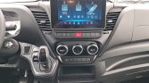 Modern car interior with a large central touchscreen, three circular climate controls, a left-side gear selector, and dashboard storage on the right.