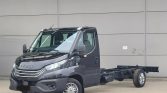 Front-side view of a black Iveco cab-chassis truck, no cargo bed, parked in front of a gray industrial wall.