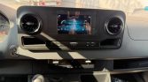 Car dashboard with touchscreen infotainment center, circular air vents, and gear lever in the foreground