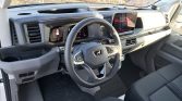 Interior of a modern pickup truck: steering wheel with controls, digital instrument cluster, and a large center touchscreen display