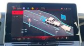 Infotainment screen showing a road scene with a white pickup towing a trailer, a 60 km/h sign, and climate controls below.