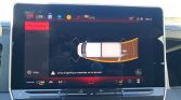 Car infotainment screen showing parking assist with a top‑down car diagram and orange sensor arcs in front and behind.