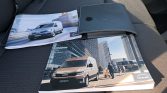 Two MAN van brochures on a car seat with a black leather binder resting on top.