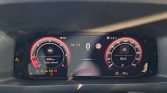 Digital car instrument cluster showing speed 0 km/h, tachometer on left, and fuel/range indicators with warning lights visible