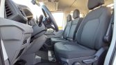 Interior of a modern vehicle cabin: driver’s seat and two passenger seats with steering wheel visible from the open driver’s side door