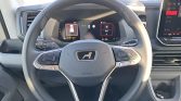 Close-up of a car steering wheel with built-in controls and a digital instrument display behind it.