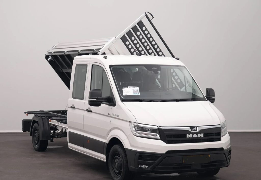 White MAN commercial van with a raised tipping bed, a heavy-duty utility truck ready for loading or unloading materials.